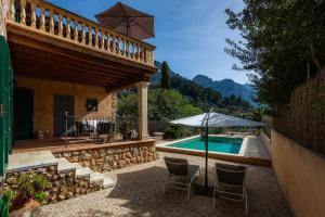 patio con sedie e ombrellone accanto alla piscina di Can Bordoy a Fornalutx