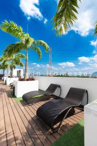 une terrasse avec deux chaises et un palmier dans l'établissement Modern Comfy Suite Room-9Pax, à Perai