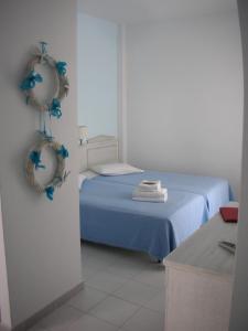 Un dormitorio con una cama azul con adornos azules en la pared en El Sol Hotel, en Kapsálion