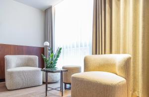 two chairs and a table in a room with a window at HasHotel in Hasselt