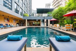einen Pool in einem Gebäude mit blauen Kissen in der Unterkunft Galleria 12 Sukhumvit Bangkok by Compass Hospitality in Bangkok