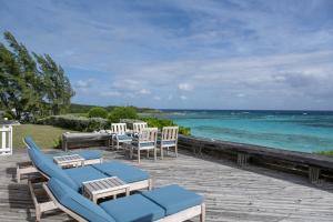 una terraza con sillas y mesas y el océano en Palm Hill House home en Rock Sound