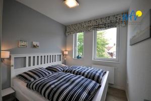 ヴァンガーオーゲにあるResidenz Helena Ferienwohnung 6のベッドルーム1室(ストライプ枕付きのベッド1台、窓付)