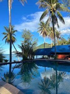 una piscina con palmeras y el océano en Cozy house in Chaloklum, en Mae Haad
