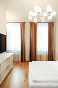 a bedroom with a bed and a television and windows at Roze Center Apartments in Liepāja