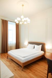 a bedroom with a large white bed with a chandelier at Roze Center Apartments in Liepāja