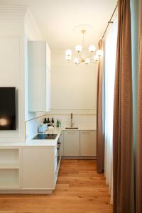 una cocina con armarios blancos y fregadero en Roze Center Apartments, en Liepāja