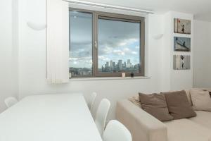 sala de estar con sofá blanco y ventana en 2 Bedroom East London Apartment With Amazing Views en Londres