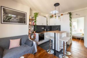 a living room with a couch and a kitchen at Secrétan - Charmant appartement au pied des Buttes Chaumont in Paris