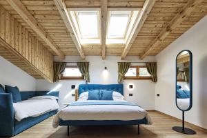 a bedroom with two beds and a blue couch at Locanda Boton D'Oro in Auronzo di Cadore