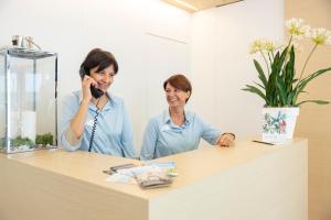 two women talking on a phone at a reception desk at Hotel Bahia in Lignano Sabbiadoro