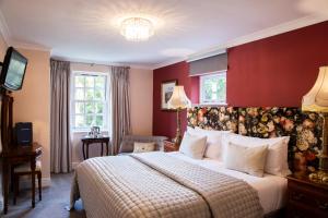 a bedroom with a large bed with a red wall at Haytor Hotel in Torquay