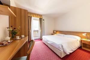 a hotel room with a large bed and a desk at Hotel Plank in San Martino di Castrozza