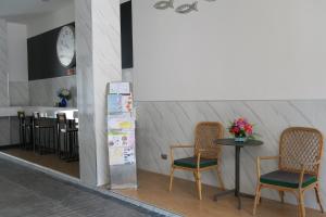 The Mira Hotel Chiang Rai في شيانج راي: كرسيين وطاولة في غرفة مع ساعة