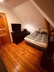 een slaapkamer met een bed en een houten vloer bij Leilighet midt på Solsiden in Trondheim