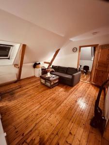 een woonkamer met een bank en een houten vloer bij Leilighet midt på Solsiden in Trondheim
