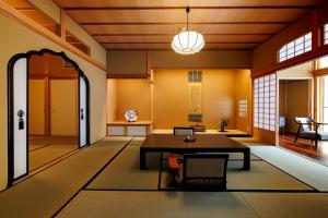 uma sala de estar com uma mesa e cadeiras e uma porta em Shoraiso em Yamanouchi