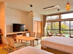 a hotel room with two beds and a table and a television at KOUBOUNOYU HONTEN in Shizuoka