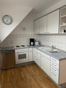 una cocina con electrodomésticos blancos y un reloj en la pared en Ferienwohnung, en Weitersburg