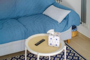 a room with a blue couch and a table with a remote at Voiles de Golfe in Vallauris