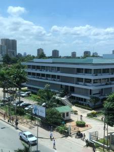 un grand bâtiment blanc avec des voitures garées dans un parking dans l'établissement Hotel Raha Tower, à Dar es Salaam