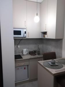 een kleine keuken met witte kasten en een magnetron bij Studio vitez in Mirijevo