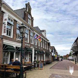 two people sitting on a bench in front of a building at Herberg de Wildeman in Lemmer