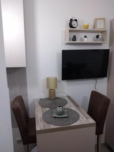een kamer met een tafel met stoelen en een televisie bij Studio vitez in Mirijevo
