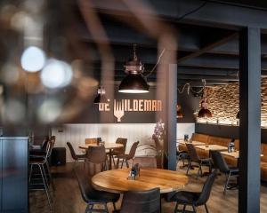 Herberg de Wildeman في ليمير: غرفة طعام مع طاولات وكراسي خشبية