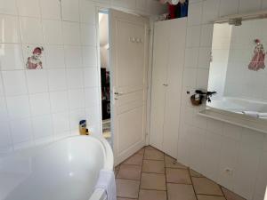 a white bathroom with a tub and a sink at les chambres de la grange in Saint-Germain-de-la-Grange
