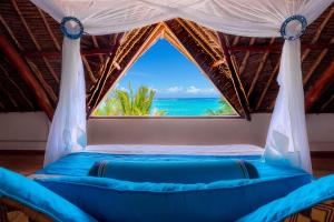 een bed met een raam met uitzicht op de oceaan bij Waterlovers Beach Resort in Diani Beach