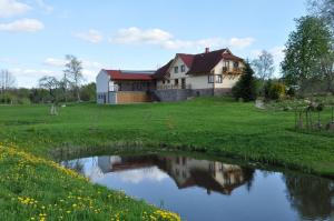 a house with a pond in front of it at Viesu nams Bezdubeņi in Sukturi
