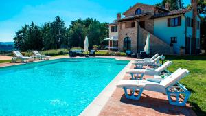 a swimming pool with lounge chairs and a house at LA TORRE DEI FAGIANI 8&2 Emma Villas in Castiglione del Lago