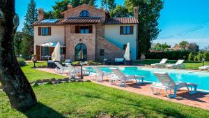 a villa with a swimming pool with chairs and a house at LA TORRE DEI FAGIANI 8&2 Emma Villas in Castiglione del Lago