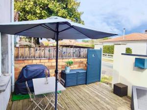 een paraplu op een terras met een tafel en een deur bij Jolie Maisonnette avec terrasse en bois in Saint-Médard-en-Jalles