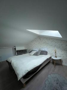 um quarto com uma grande cama branca e uma mesa em Jolie Maisonnette avec terrasse en bois em Saint-Médard-en-Jalles
