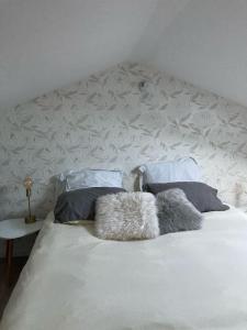 a white bed with two pillows on top of it at Jolie Maisonnette avec terrasse en bois in Saint-Médard-en-Jalles