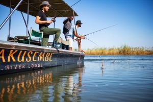 two men fishing on a boat on the water at Hakusembe River Camping2Go in Kansukwa