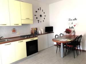 een keuken met witte kasten en een tafel met stoelen bij Irina’s house with view on like and swimming pool in Riva di Solto
