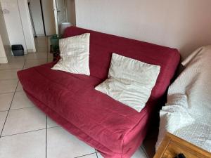 a red couch with two white pillows on it at Appartement plein centre in Antibes