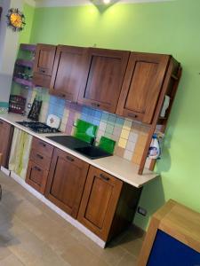 a kitchen with wooden cabinets and a green wall at Violet Home Irpinia in Montemarano