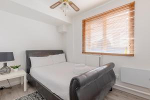 a bedroom with a bed and a couch and a window at Well Located 2BD Flat 20 Mins to Tower Bridge! in London