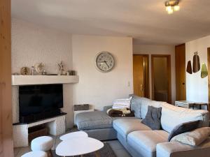 sala de estar con sofá y reloj en la pared en Greppons COSY & MOUNTAIN apartments by Alpvision Résidences, en Veysonnaz