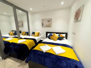 two beds in a room with yellow and blue at Tower Bridge, London Luxury Flat with Beautiful Garden Views in London