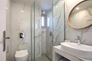 y baño con ducha, lavabo y espejo. en Villaggio Mare Suites en Kalamaki