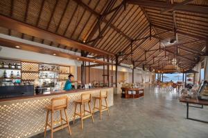 a restaurant with a bar with a woman in the background at Lembongan Beach Club & Resort in Nusa Lembongan