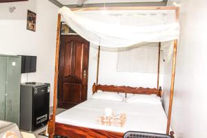 1 dormitorio con 1 cama con dosel en ANNA APARTMENTS MTWAPA, en Mtwapa