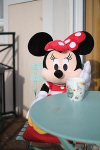 um brinquedo de rato Mickey sentado numa mesa com um copo em Apart' Minnie - Disneyland Paris - 3 Bedrooms - Parking privé em Magny-le-Hongre