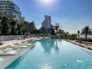 una grande piscina con sedie bianche e palme di Remarkable 2BR+storage in JBR with Sea View a Dubai