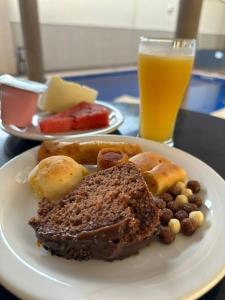 ein Teller mit Lebensmitteln auf einem Tisch mit einem Glas Orangensaft in der Unterkunft Serra's Palace Hotel in Parauapebas